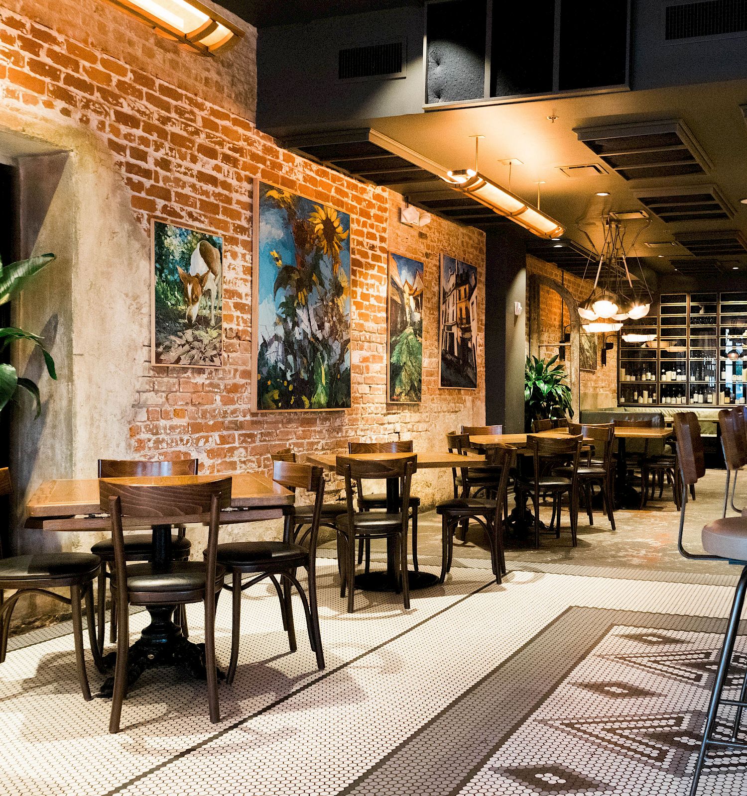 A cozy restaurant interior with exposed brick, artwork, and wooden furniture.