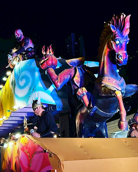 Colorful parade float with mythical horse and festive decorations at night.