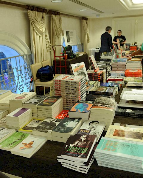 People are browsing books laid out on tables possibly at a book sale or event.
