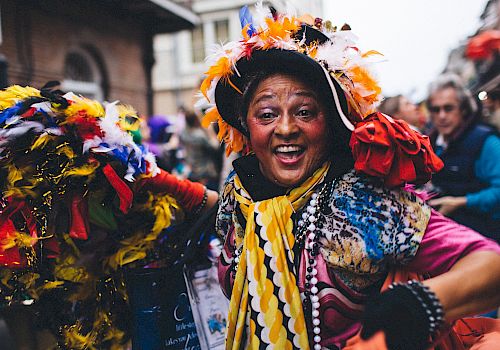 A joyful person in vibrant, festive attire is likely enjoying a carnival or parade.